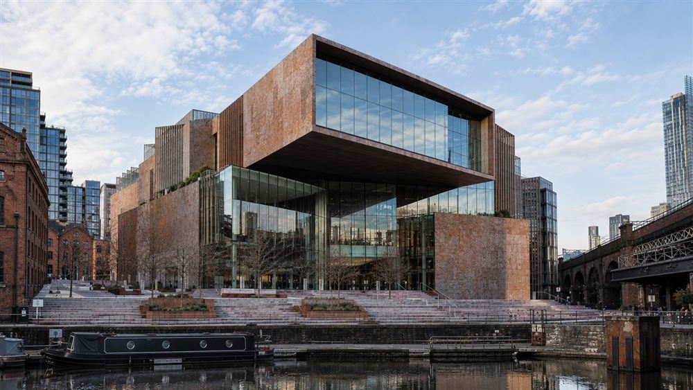 The Living Archive: a stone and bronze cultural centre with a cantilevered gallery beside the Castlefield canal in Manchester
